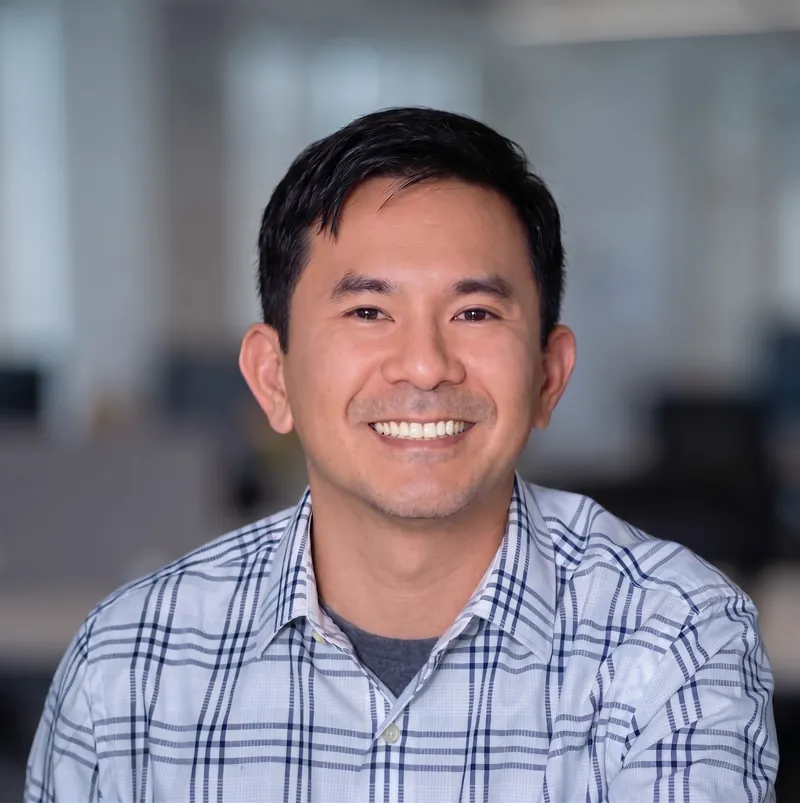 Tai Nguyen, smiling, in a plaid shirt